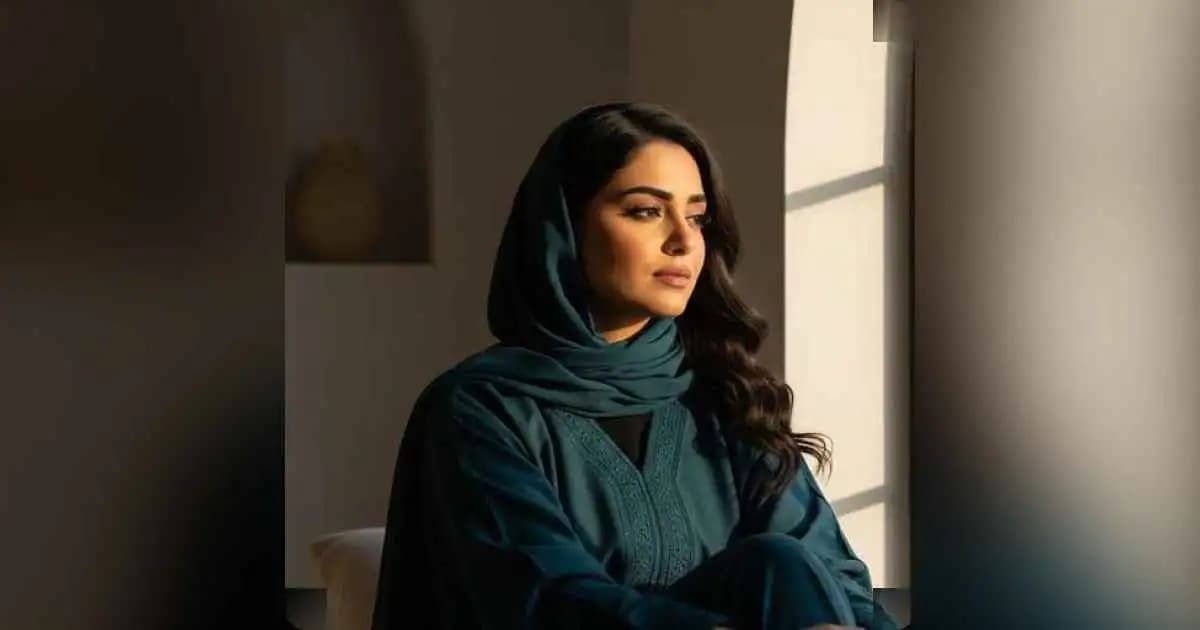 A Middle Eastern woman sitting in quiet reflection, looking out a window