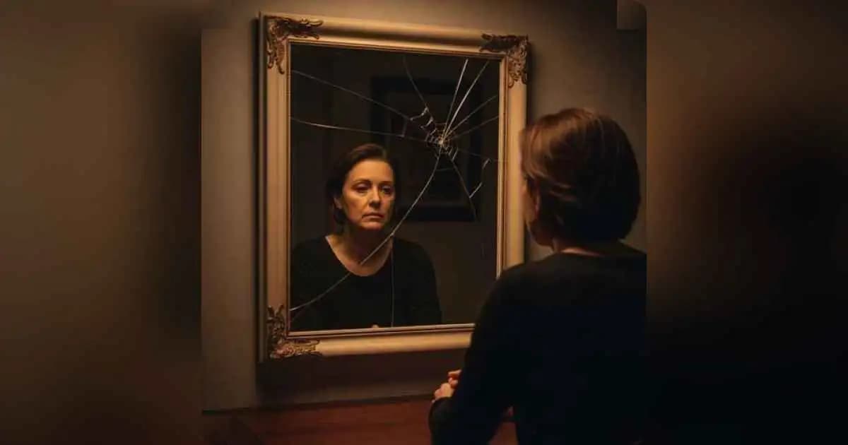 A person looking at their reflection in cracked glass