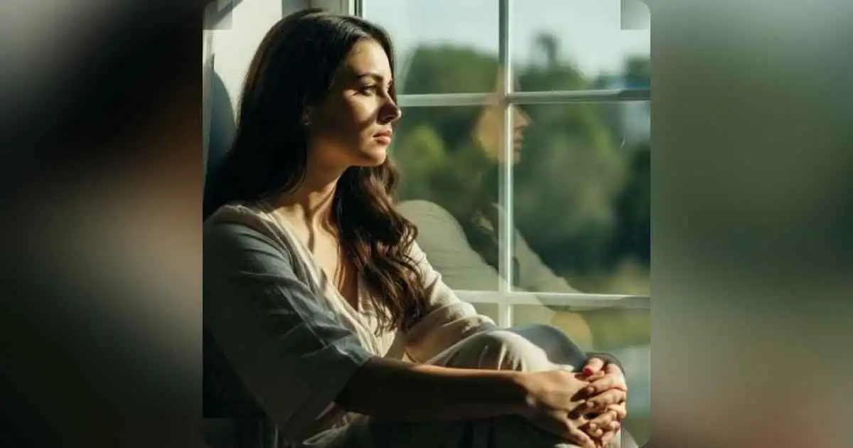 A person sitting alone, looking out a window, deep in thought